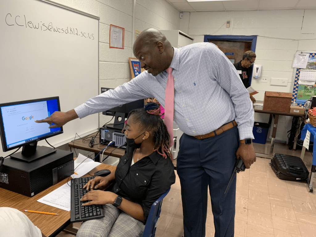 A teacher pointing to a student's computer screen