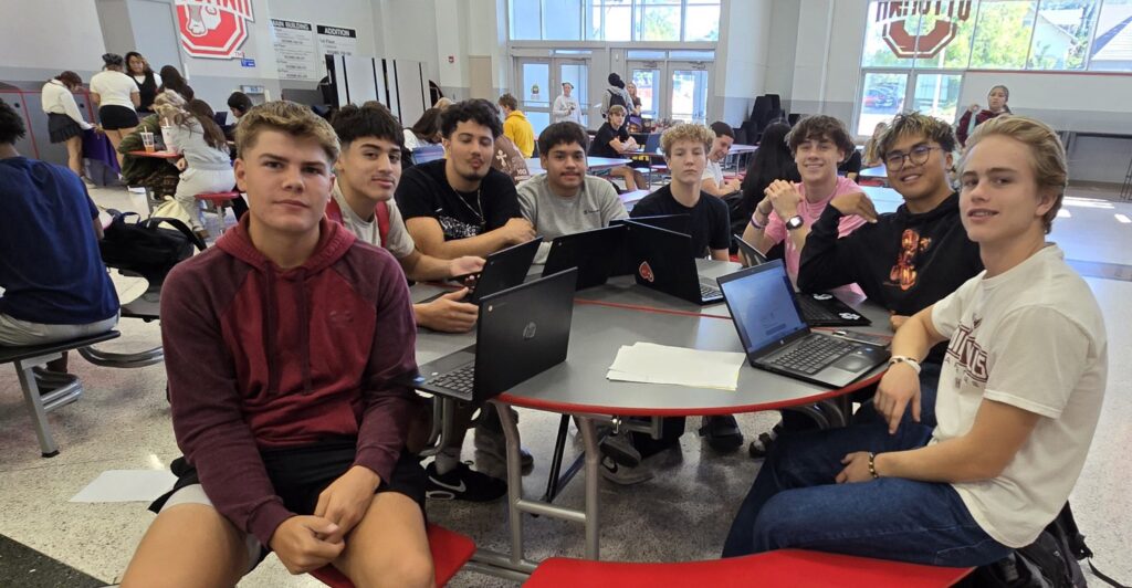 Students gathered around laptops in a classroom