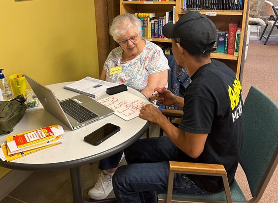 A student and Presentation Lantern Center staff member sit at a table talking.